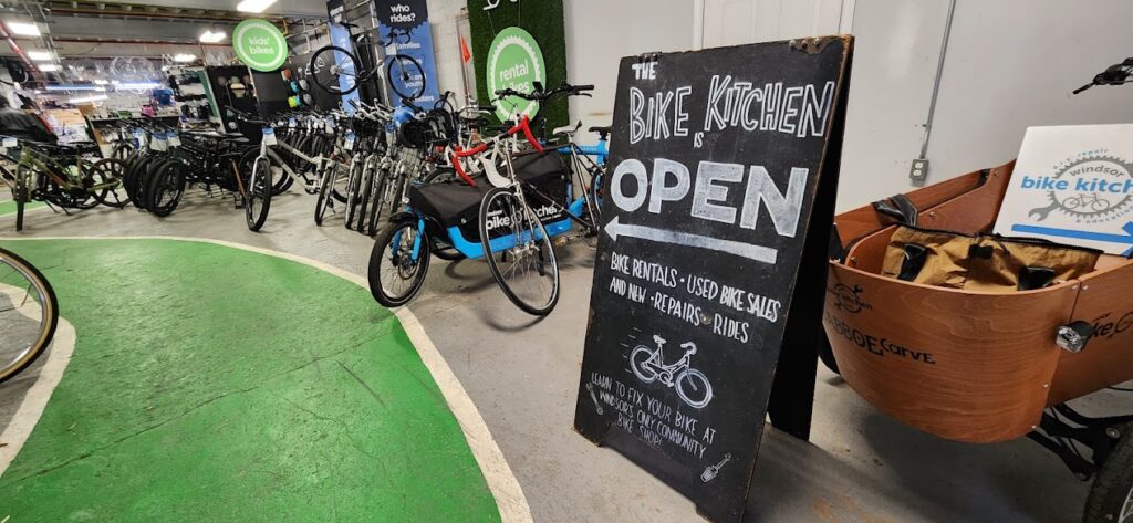 some bikes in the background with a sign in the foreground that says 'bike kitchen open'